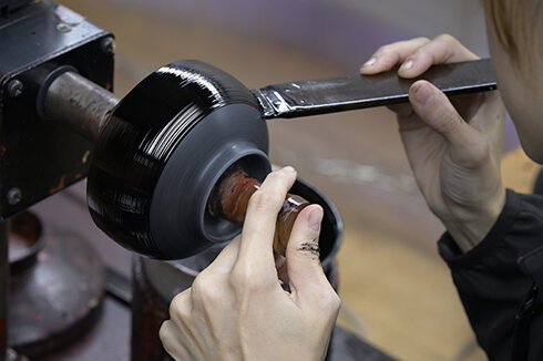 塗っては次へ、塗っては次へ。刷毛目を残さないように1点ずつ丁寧に仕上げていく。