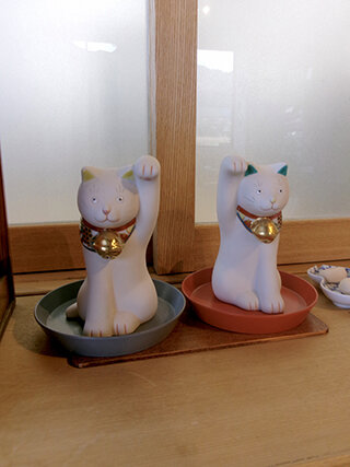 RIN&CO.の器にちょこんと乗った上出長右衛門窯の招き猫。漆の保管に九谷焼の器を使用しているそうで、意外な繋がりに出会う。